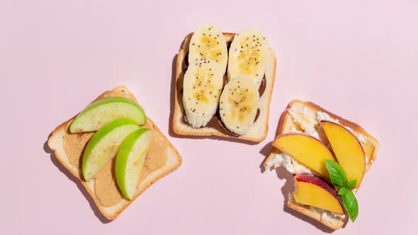 Set of toasted bread with peach, apple and banana on pink background. Stop Motion Animation.