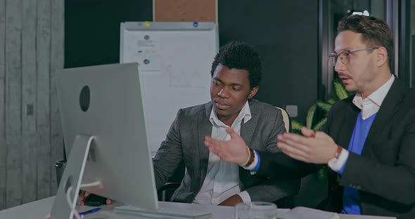 European and African in the Office in Front of the Computer Showing Happy Emotions