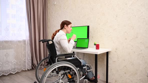 Caucasian Woman with Disabilities Working at the Computer While Sitting in a Wheelchair