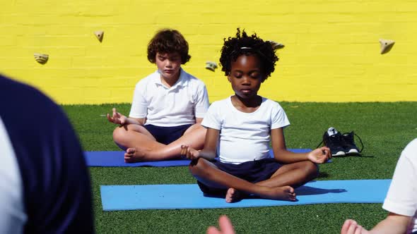 Yoga instructor instructing children in performing yoga