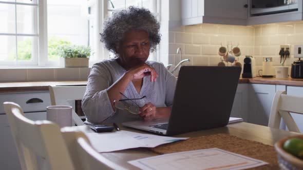 Senior african american woman using laptop and calculating finances at home