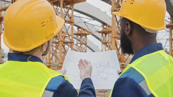 Two Male Construction Workers Discussing Blueprint