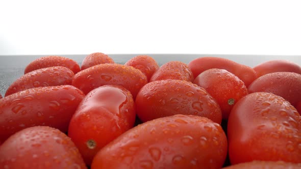 Ripe Red Biological Tomatoes in a Row on a Smooth Glass Surface