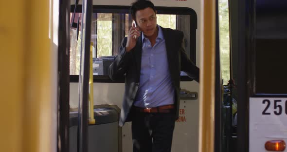 Business commuter talking on mobile phone while getting out from bus 4k