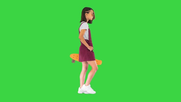 Girl Holding a Skateboard and Walking on a Green Screen Chroma Key