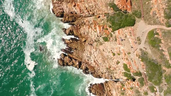 Top down view of waves crashing into rocky shore