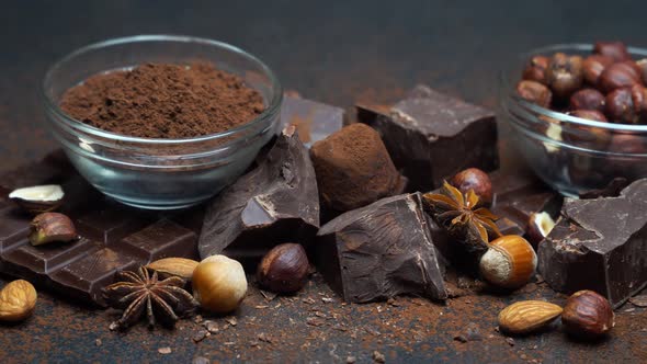 Heap of Broken Chocolate Pieces and Nuts on Dark Concrete Background