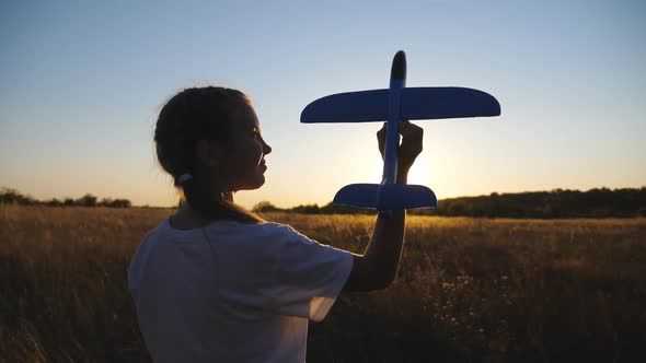 Little Female Child Stands at Grass Field Holding in Hand Toy Plane