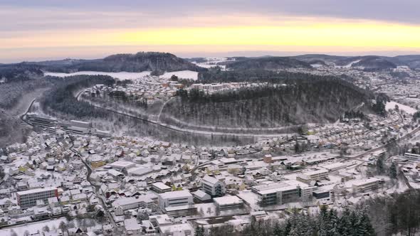 Panning shot of a drone over a white snow covered winter city in a valley. Albstadt at the Swabian A