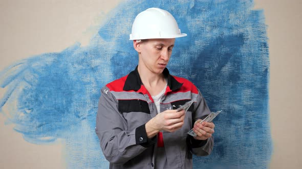 Focused Handyman Wearing Jumpsuit Counts Money in Apartment