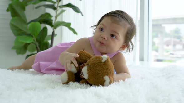 Cute cheerful girl baby toddler crawl to teddy bears to play and hug happily