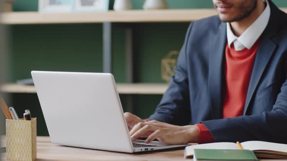 Businessman Typing on Laptop and Taking Notes