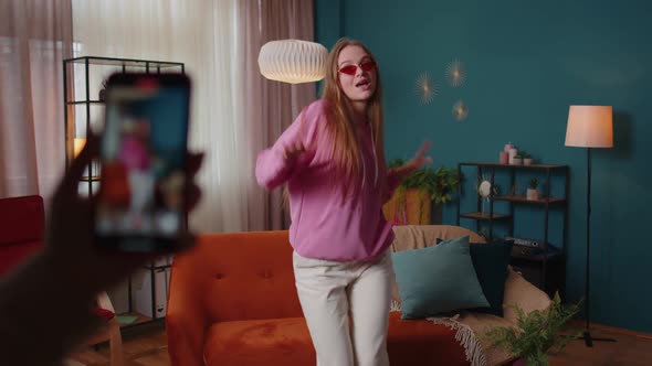 Joyful Blogger Teen Girl Dancing at Camera Filming Video Using Mobile Phone at Home in Living Room