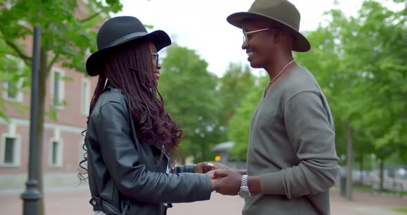 Side View of Afroamerican Couple in Love Holding Hands and Talking Outdoors