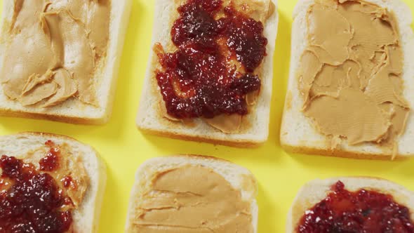 Close up of multiple peanut butter and jelly sandwiches on yellow surface