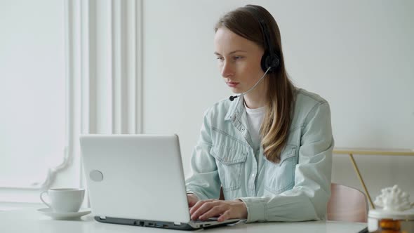 Female Talking in a Video Conference on Line with a Headset with Microphone and Using Laptop in