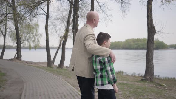 Grandfather and Grandson Standing on the Riverbank, Looking on the Water
