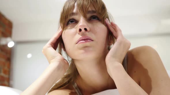 Tired Woman with Headache and Tension Lying in Bed Close Up