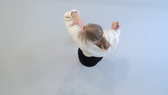 The girl dances a modern dance in a bright studio. Slow and smooth movement. View from above.