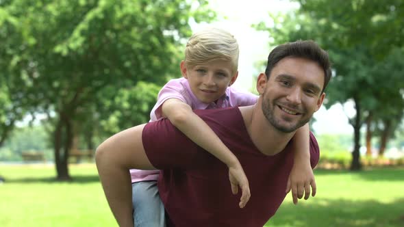 Father and Son Enjoying Piggyback Ride, Showing Thumbs Up, Support and Trust