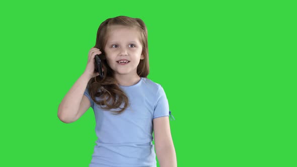 Little Schoolgirl Making a Call with a Smartphone While Walking on a Green Screen, Chroma Key