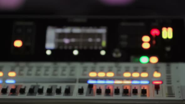 Mixing Console with Lighting Buttons, Refocused Video of Audio Equipment