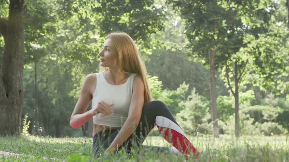 Lovely Woman Practicing Yoga on the Grass in the Park