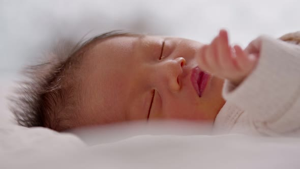 Close up happy newborn baby lying sleeps on a white blanket