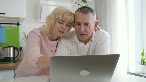 Senior Couple Using Computer on Apartment Kitchen
