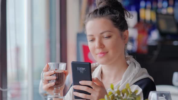 Beautiful Woman with Cup of Hot Chocolate Text Messaging with Her Mobile at Cafe