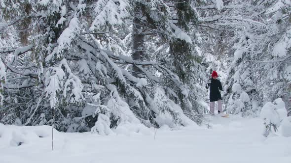 A woman walking through deep snow in forest