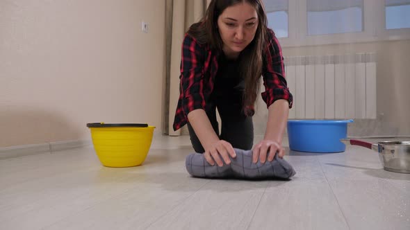Disappointed Lady Wipes Water with Rug From Floor in Room