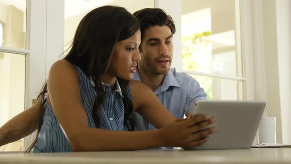 Couple interacting with each other while using digital tablet