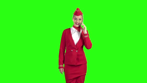 Stewardess in a Red Suit Speaks on the Phone and Steps Away . Green Screen. Slow Motion