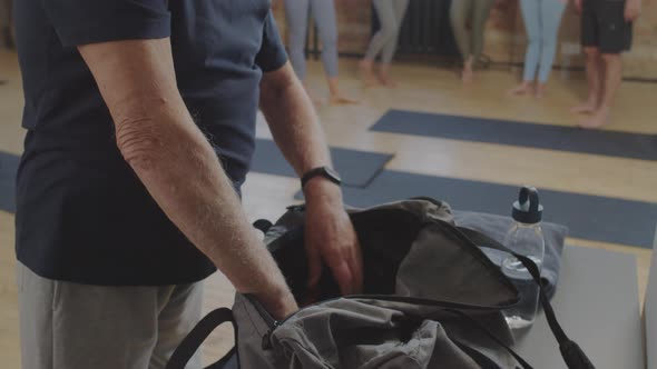 Senior Man Unpacking Bag in Yoga Studio