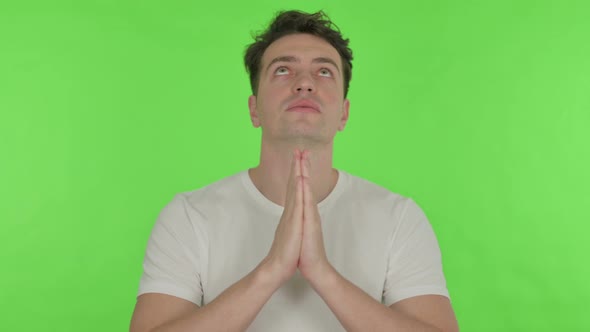 Praying Young Man Wishing to God on Green Background