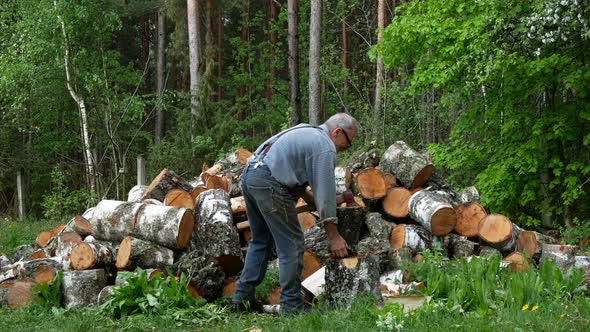 Older man is outside chopping wood with a splitting axe