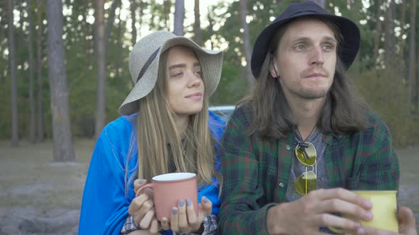 Young Couple of Tourists Sitting in the Forest Drinking Tea or Coffee. Happy Caucasian Man and Woman