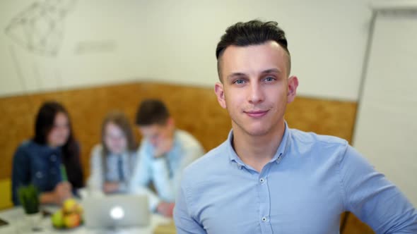 Portrait of Young Manager in the Office with His Team Is Working on Project