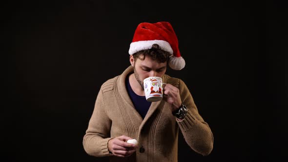A man with a Santa hat drinking and eating