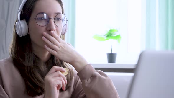 Teenage Girl with Laptop Eating Cookies While Watching a Movie