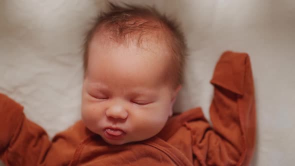 A newborn baby in a cradle, viewed from above.