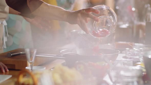 Chef Putting Tomatoes in Frying Pan during Cooking Master Class