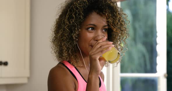 Happy woman drinking juice while listening to music