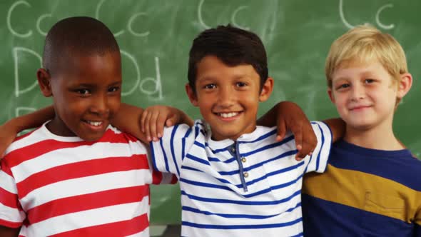 School kids standing together with arm around in classroom