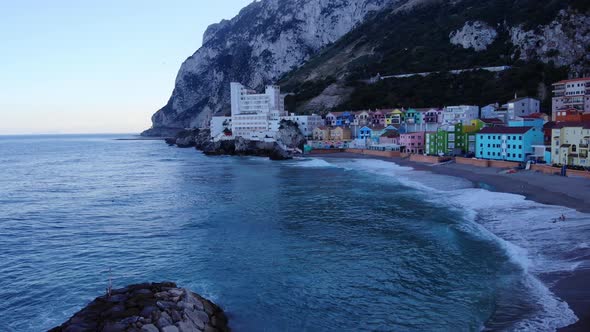 Colored Residential Buildings Of Catalan Bay Revealed Sea Walls In Gibraltar. Aerial Tilt-down Shot