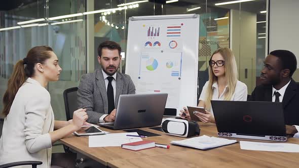 Businessmen and Businesswomen Sitting Together at the Meeting Table and Working