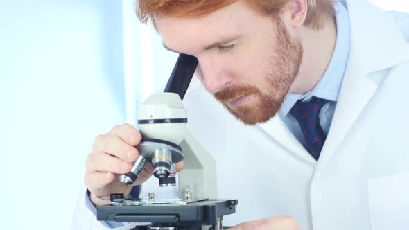 Redhead Doctor Working on Microscope in Laboratory