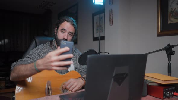 Smiling Influencer Musician Texting and Taking a Selfie at His Home Studio