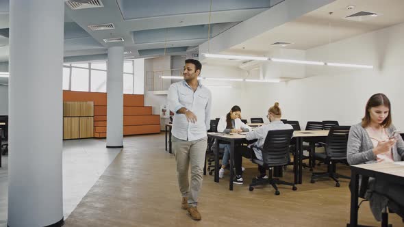 Young Male is Smiling and Dancing Clapping Hands Walking Along Modern Office with Diverse Colleagues